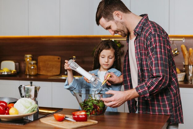 Seitenansicht des Vaters mit der Tochter, die Essen in der Küche zubereitet