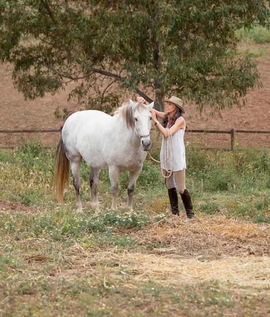 Seitenansicht des weiblichen Bauern, der ihr Pferd streichelt