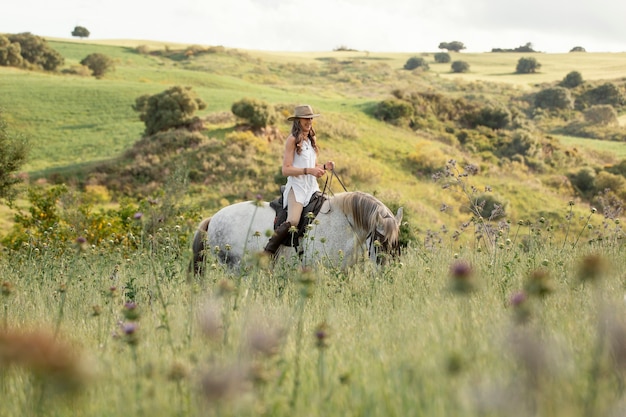 Seitenansicht des weiblichen Bauernreitens reiten in der Natur