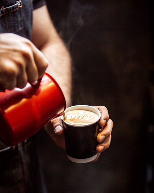 Seitenansicht, die ein Mann aus Sahne-Tasse Cappuccino zieht