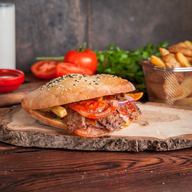 Seitenansicht Döner mit Tomaten und Bratkartoffeln und Gemüse in Bordkochgeschirr