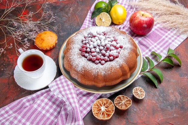 Seitenansicht ein Kuchen ein Kuchen eine Tasse Tee Cupcake Apfel Zitronen mit Blättern auf der Tischdecke