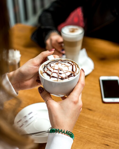 Seitenansicht ein Mädchen trinkt Cappuccino