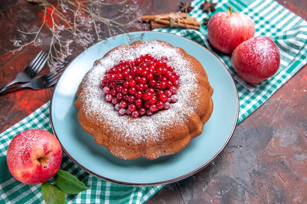 Seitenansicht einen Kuchen ein Kuchen Äpfel mit Blättern auf der karierten Tischdecke Zimtgabeln