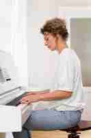 Kostenloses Foto seitenansicht einer blonden frau, die das klavier spielt