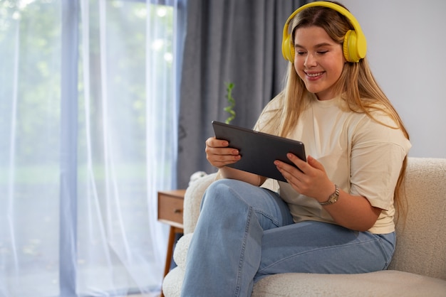 Kostenloses Foto seitenansicht einer frau, die videoanrufe mit einem tablet tätigt