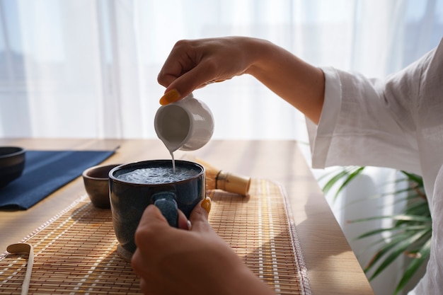 Kostenloses Foto seitenansicht einer frau, die zu hause blauen matcha genießt