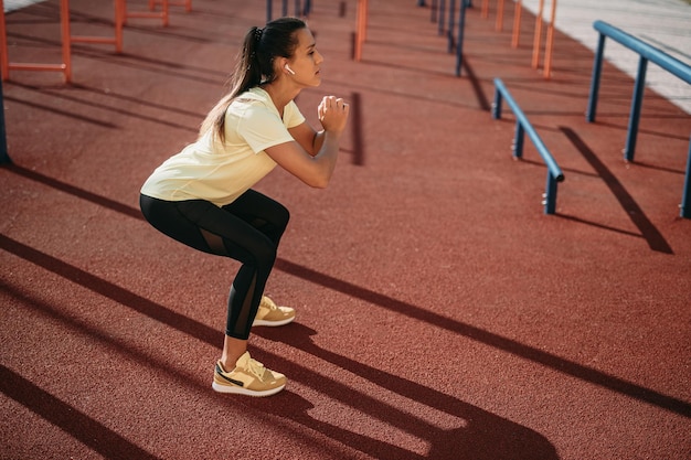 Seitenansicht einer Frau in Activewear, die an der frischen Luft hockt