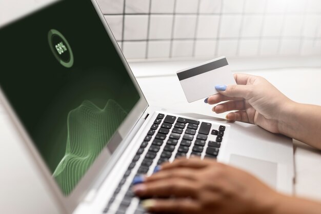 Seitenansicht einer Frau mit Laptop für Online-Shopping mit Kreditkarte