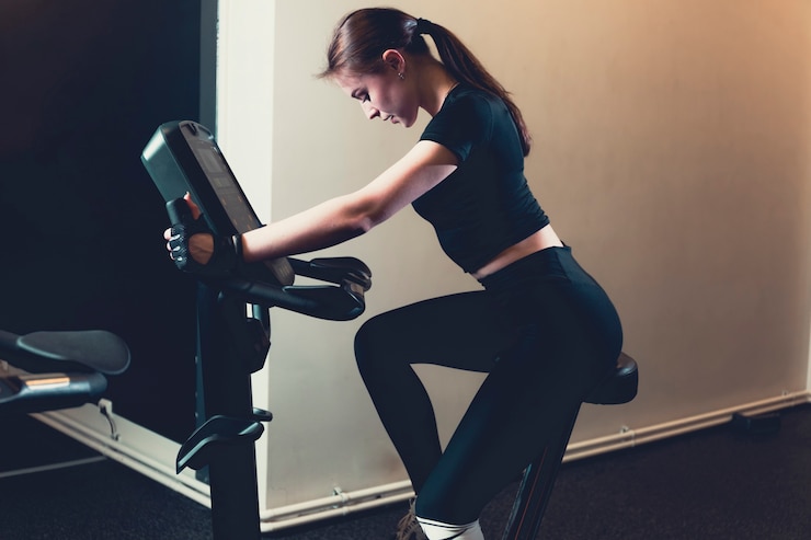 Kostenlose Foto seitenansicht einer jungen frau, die ein hometrainer fährt