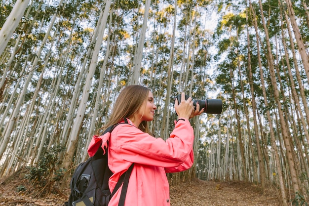 Seitenansicht einer jungen Frau, die im Wald fotografiert