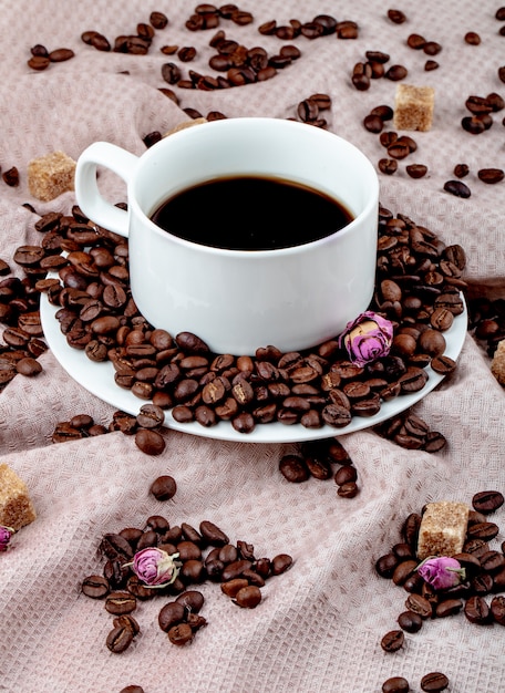 Seitenansicht einer Tasse Kaffee mit Kaffeebohnen und braunen Zuckerwürfeln