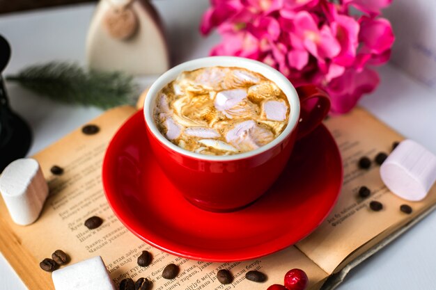 Seitenansicht einer Tasse Kaffee mit Marshmallows und Kaffeebohnen auf dem Tisch