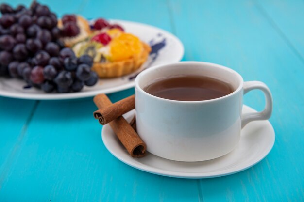 Seitenansicht einer Tasse Tee mit Zimtstangen auf einem blauen hölzernen Hintergrund