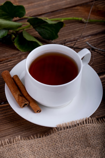 Seitenansicht einer Tasse Tee mit Zimtstangen auf einem Holz