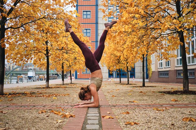 Seitenansicht eines attraktiven Mädchens in Sportkleidung, das Yoga-Übungen auf der Straße der Stadt macht