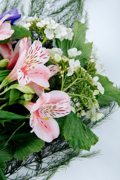 Seitenansicht eines Blumenstraußes der rosa Farbe alstroemeria Blumen mit dunkelviolettem Irisblühviburnum auf weißem Hintergrund