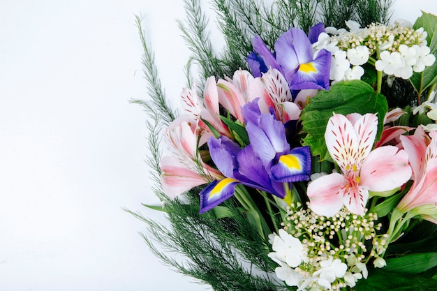 Seitenansicht eines Blumenstraußes der rosa Farbe Alstroemeria Blumen mit dunkelvioletter Iris, die Viburnum und Spargel auf weißem Hintergrund blüht