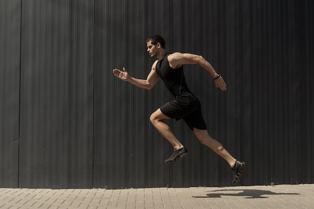Seitenansicht eines fitten jungen, athletischen Mannes, der springt und läuft.