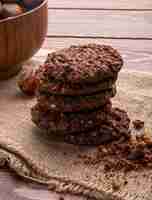 Kostenloses Foto seitenansicht eines haufens von schokoladenkeksen mit getreidenüssen und kakao auf holz