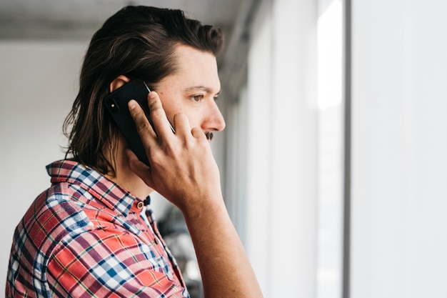 Seitenansicht eines jungen Mannes, der am Handy spricht