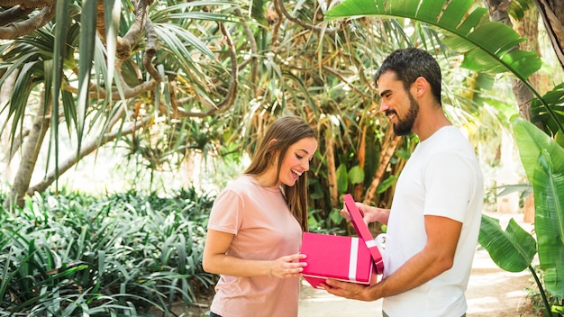 Seitenansicht eines jungen Mannes, der seiner Freundin Geschenk zeigt