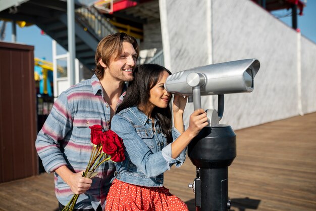 Seitenansicht eines jungen Paares bei einem Date im Freien, das durch das Teleskop schaut