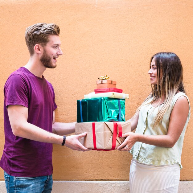 Seitenansicht eines lächelnden jungen Paarholdingstapels Geschenke