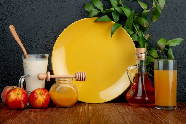 Seitenansicht eines leeren gelben Tellers und der frischen reifen Nektarinen mit einer Flasche Olivenöl