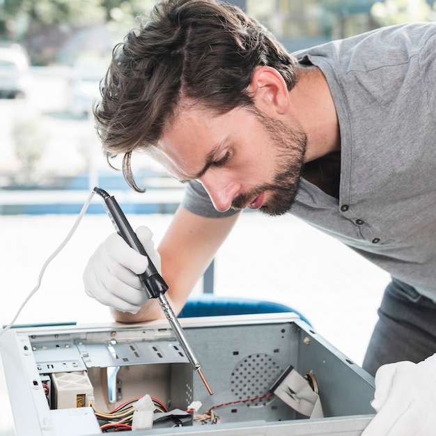 Seitenansicht eines männlichen Technikers, der Computer-CPU in der Werkstatt repariert