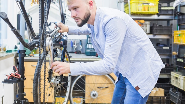 Seitenansicht eines Mannes, der Fahrrad repariert