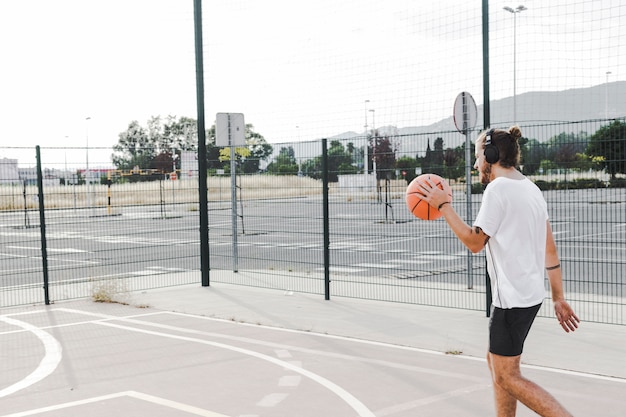 Seitenansicht eines Mannes, der vor Gericht mit Basketball geht