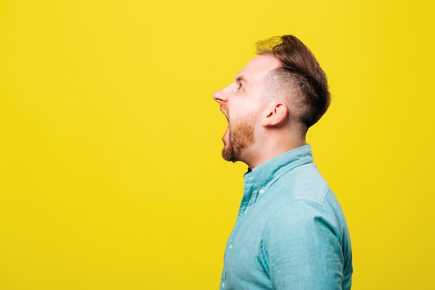 Seitenansicht eines schockierten mannes beim schreien isoliert auf gelbem hintergrund studioaufnahme