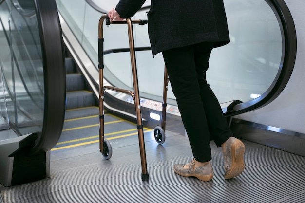 Seitenansicht Erwachsener mit Gehhilfe in der Nähe von Rolltreppen