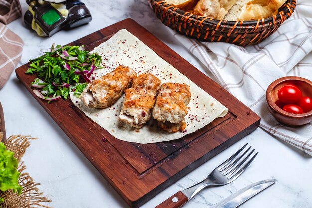 Seitenansicht Fleisch Lula Kebab auf Fladenbrot mit Kräutern und Zwiebeln auf einem Brett