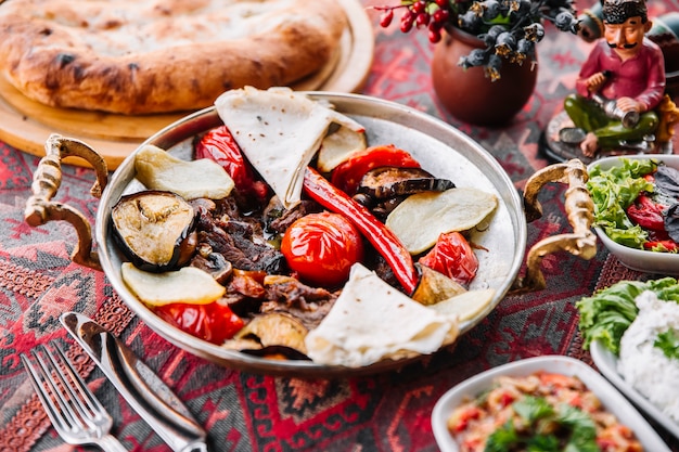 Kostenloses Foto seitenansicht fleisch salbei mit fladenbrot tomaten und salate auf dem tisch