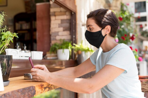 Seitenansicht Frau an der Terrasse mit Maske