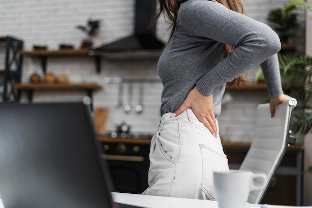 Seitenansicht Frau, die Rückenschmerzen während der Arbeit von zu Hause aus hat