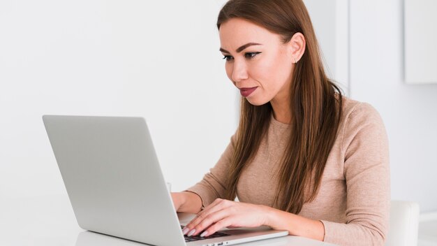 Seitenansicht Frau, die von zu Hause auf ihrem Laptop arbeitet