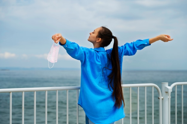 Seitenansicht Frau mit Gesichtsmaske am Meer