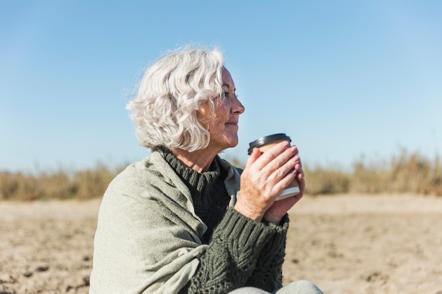 Kostenloses Foto seitenansicht frau mit kaffee im freien