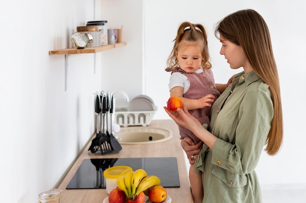 Kostenloses Foto seitenansicht frau mit kind in der küche
