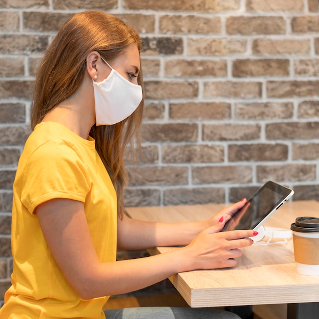 Seitenansicht Frau mit Tablette tragende Maske