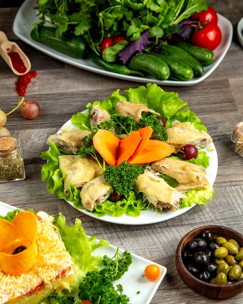 Seitenansicht gekochtes Huhn mit Kräutern auf Salatblatt mit Karottenscheiben