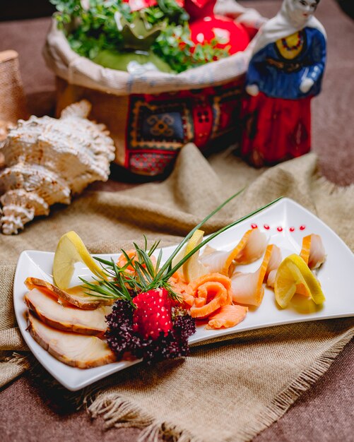 Seitenansicht geräucherter Fischteller Balyk Lachs mit Kräutern Granatapfel und Zitronenscheiben