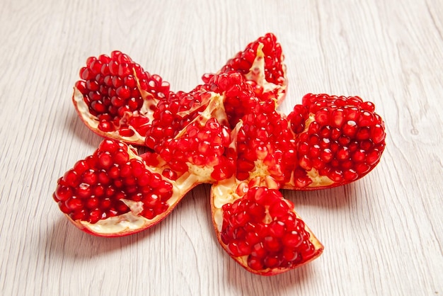 Kostenloses Foto seitenansicht geschälter granatapfel geschälter granatapfel neben den beeren auf dem weißen tisch