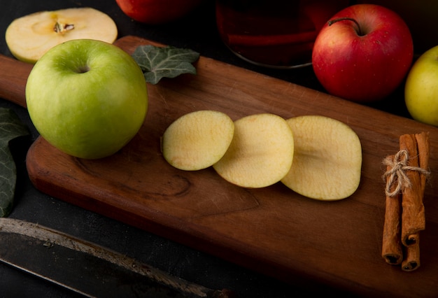 Seitenansicht geschnittener grüner Apfel mit Zimt-Efeublatt auf einem Brett grüne und rote Äpfel