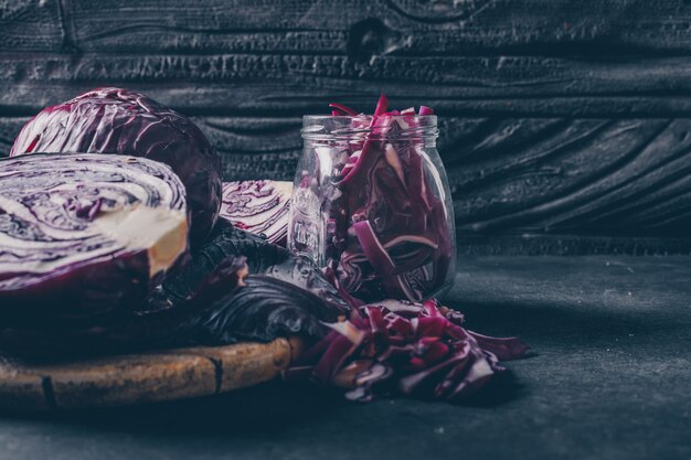 Seitenansicht geschnittener Rotkohl im Glas auf dunklem strukturiertem Hintergrund. Vertikale