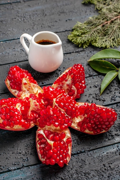 Seitenansicht Granatäpfel gepillt Granatapfelöl neben den Fichtenzweigen auf dem dunklen Tisch