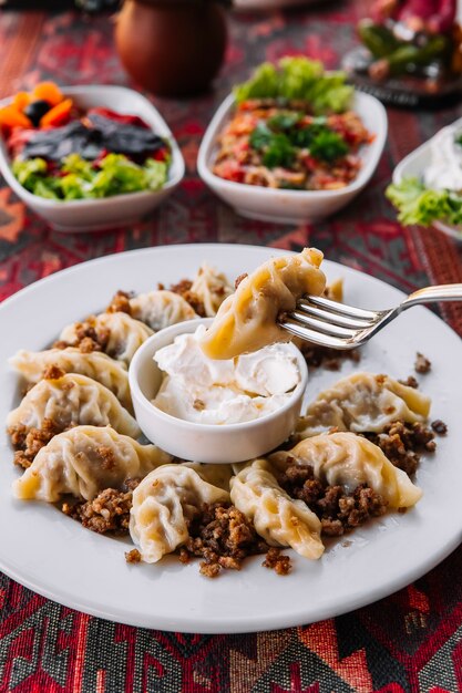 Seitenansicht Gurza Lammknödel mit saurer Sahne auf einem Teller